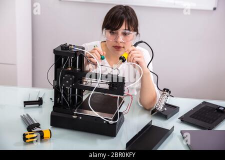 Female Engineer Or Tech Repairs Electronic Device In Hardware Repair Shop Stock Photo