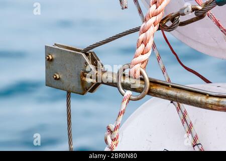 Steel rope and rusty hook on the back side of the sailing boat. Flag of Greece and historical castle on the background . Stock Photo