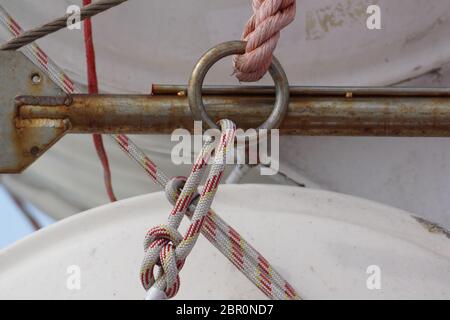 Steel rope and rusty hook on the back side of the sailing boat. Flag of Greece and historical castle on the background . Stock Photo