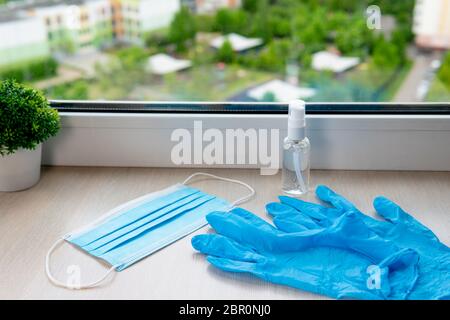 Blue medical gloves, mask and antiseptic gel on the windowsill Stock Photo