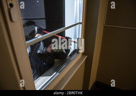 Thief Trying To Break The Window With Crowbar At Night Stock Photo