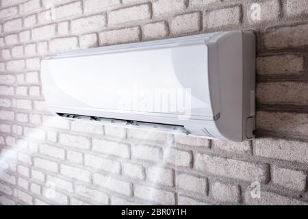 White Air Conditioner Blowing Cold Air On Brick Wall In Living Room Stock Photo