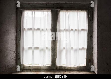 Dark old window with bricks and curtain, light coming through, darkness Stock Photo