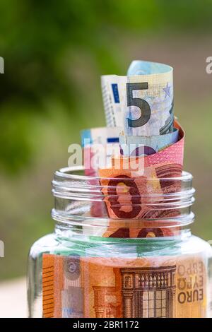Composition with saving money banknotes in a glass jar. Concept of investing and keeping money, close up isolated. Stock Photo