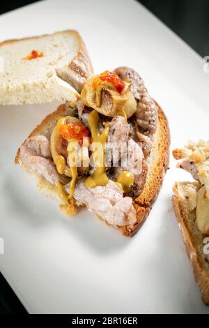 famous traditional portuguese bifana marinated spicy pork sandwich snack with mustard piri piri sauce and garlic in lisbon cafe Stock Photo