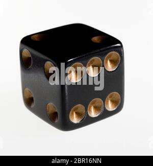 One black dice against a white background Stock Photo