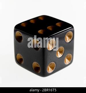 One black dice against a white background Stock Photo