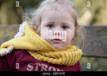 18 month old blonde toddler wearing a warm, wooly hat looking at the camera, UK Stock Photo