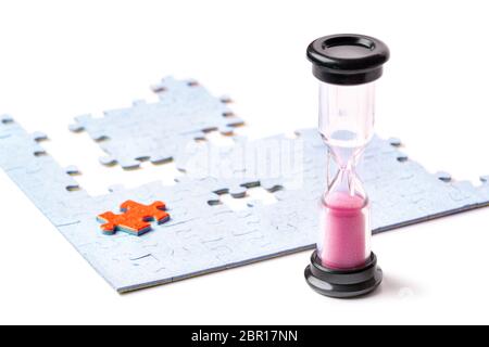 Pink and black sand hourglass on color puzzle pieces white background Stock Photo