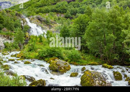 Scenery Waterfall In Briksdal Glacier In Norway. Beautiful waterfall from the meltwater of the Brixdal Glacier in Norway, bottom view. Panoramic view Stock Photo