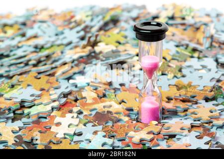 Pink and black sand hourglass on color puzzle pieces background Stock Photo