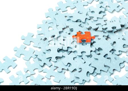 Bright orange puzzle piece and many light blue puzzle pieces background Stock Photo