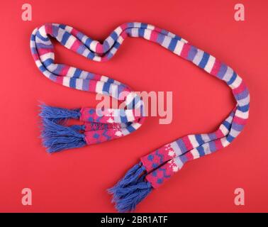 knitted multicolored scarf on a red background, top view Stock Photo