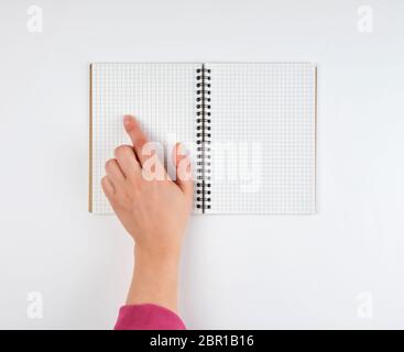 empty open notebook in a cell and female hand, white  background, top view Stock Photo