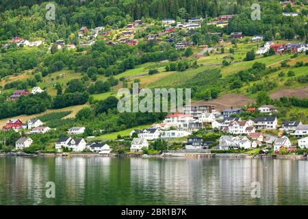 Village is located on the green slopes near lake. Scenic summer view of cottage houses in mountain village near lake, Norway. Tourism holidays and tra Stock Photo