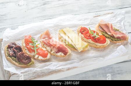 Crostini with different toppings on the wooden background Stock Photo