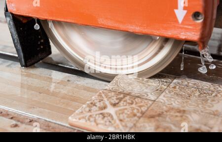 The diamond disk of a wet saw cuts through a ceramic tile. Stock Photo
