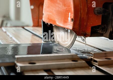 The diamond disk of a wet saw cuts through a ceramic tile. Stock Photo