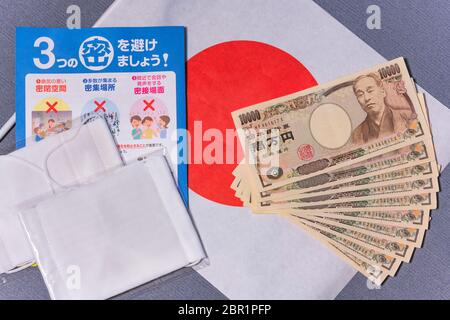 tokyo, japan - may 20 2020: Cloth masks with leaflet promoting social distancing and 100,000 yen in cash sent by the Japanese govt to fight coronaviru Stock Photo