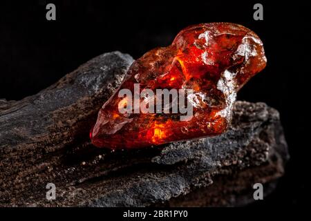 A piece of yellow semi transparent natural amber, classification color honey or cognac, has cracks on its surface. Polished, natural shape. Placed on Stock Photo