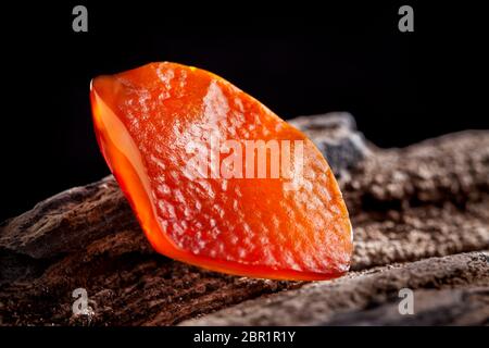 A piece of yellow semi transparent natural amber, classification color honey or cognac, has cracks on its surface. Polished, natural shape. Placed on Stock Photo