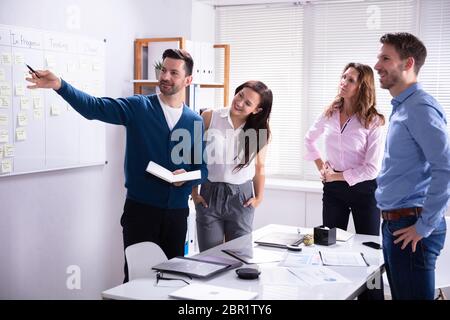 Young Male And Female Businesspeople Standing Near Scrum Task Board In Office Stock Photo