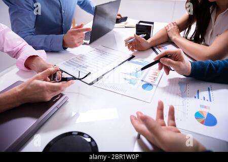 Close-up Of Business Colleagues Working Together With Data Analysis Paper On Desk Stock Photo