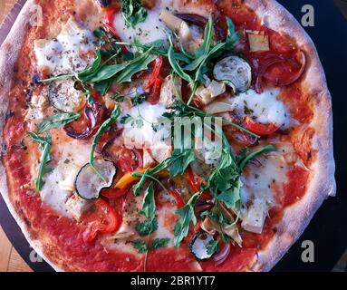 Cooked Mediterranian style wood fired pizza topped with fresh rocket Stock Photo