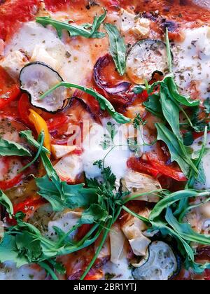 Cooked Mediterranian style wood fired pizza topped with fresh rocket Stock Photo