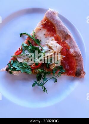 Cooked Mediterranian style wood fired pizza topped with fresh rocket, single portion Stock Photo