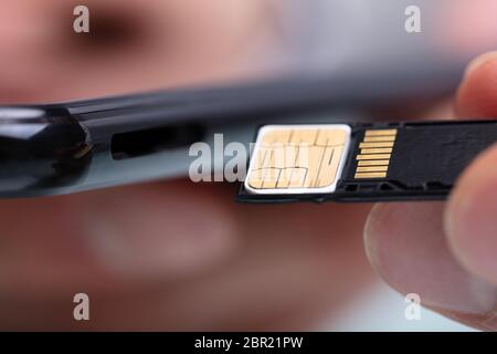 Close-up Of Person Inserting Sim Card And Memory Card In Mobile Phone Stock Photo