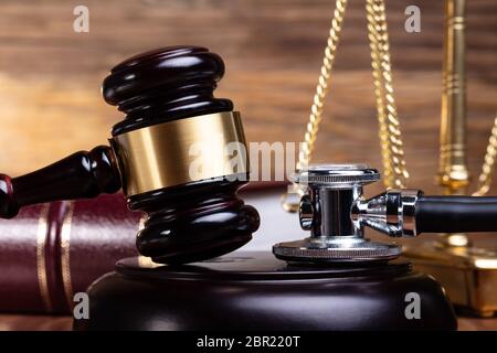 Close-up Of Stethoscope And Gavel In Front Justice Scale On Wooden Desk Stock Photo
