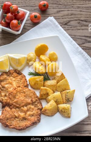 Portion of schnitzel with garnish on the wooden table Stock Photo