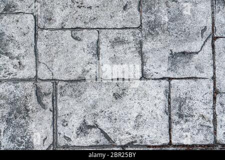 the background is a textured gray stone. Old pavement close-up view from above, blocks of stones. Stock Photo