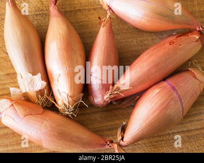 Seven echalion shallots on a wooden chopping board Stock Photo
