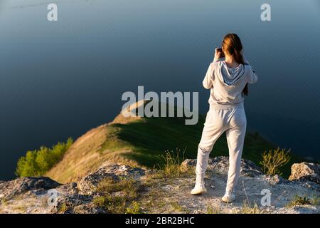 Young woman with camera takes photo. Blogger photoshoot concept. Tourist travels Stock Photo
