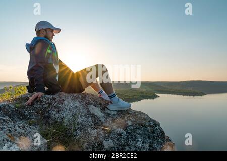 Man in sportswear and hat on a top of rock ower beautiful canyon river landscape Stock Photo