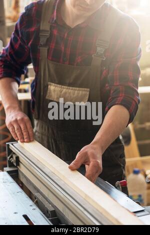 The worker makes measurements of a wooden board with corner ruler. Profession, carpentry and woodwork concept. Stock Photo