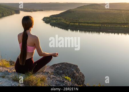 Sport girl doing yoga in mountains beautiful landscape. Young woman leads healthy lifestyle, meditates Stock Photo