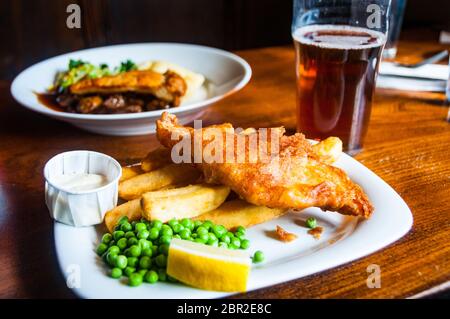 A traditional British pub meal with fish and chips and a steak and mushroom pie along with a pint of bitter.