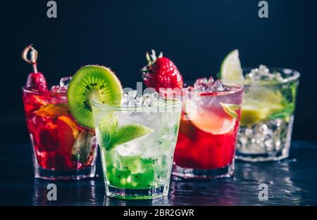 Four colorful tasty alcoholic cocktails in a row at the bar stand. Luxury vacation concept. Toned image Stock Photo