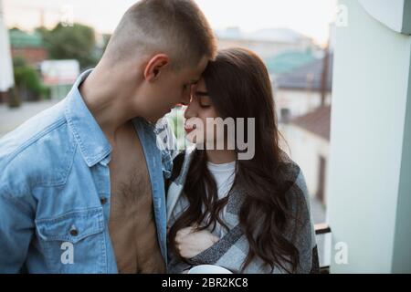 Standing on the balcony, hugging, tender moments. Quarantine lockdown, stay home concept - beautiful caucasian couple enjoying new lifestyle during coronavirus. Happiness, togetherness, healthcare. Stock Photo