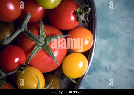 Colourful tomatoes on a pewter plate over old, painted wood background Stock Photo