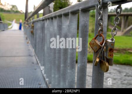 Different ages padlocks on the metal bridge in Latvia. Wedding tradition. Rusty locks on the bridge hanging chain. Stock Photo