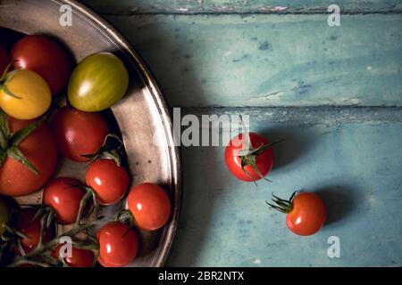 Colourful tomatoes on a pewter plate over old, painted wood background Stock Photo