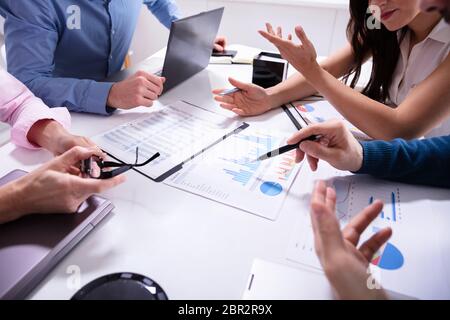 Close-up Of Business Colleagues Working Together With Data Analysis Paper On Desk Stock Photo