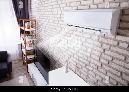 White Air Conditioner Blowing Cold Air On Brick Wall In Living Room Stock Photo