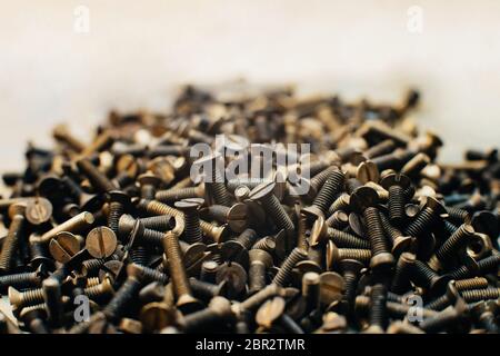 Close-up, macro. Old Soviet brass screws and nuts with countersunk head with a straight slot for a flat screwdriver. Texture, background of screws. Stock Photo
