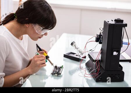 Female Engineer Or Tech Repairs Electronic Device In Hardware Repair Shop Stock Photo