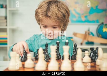 Pupil kid thinking about his next move in a game of chess. Concentrated  little boy sitting at the table and playing chess Stock Photo - Alamy